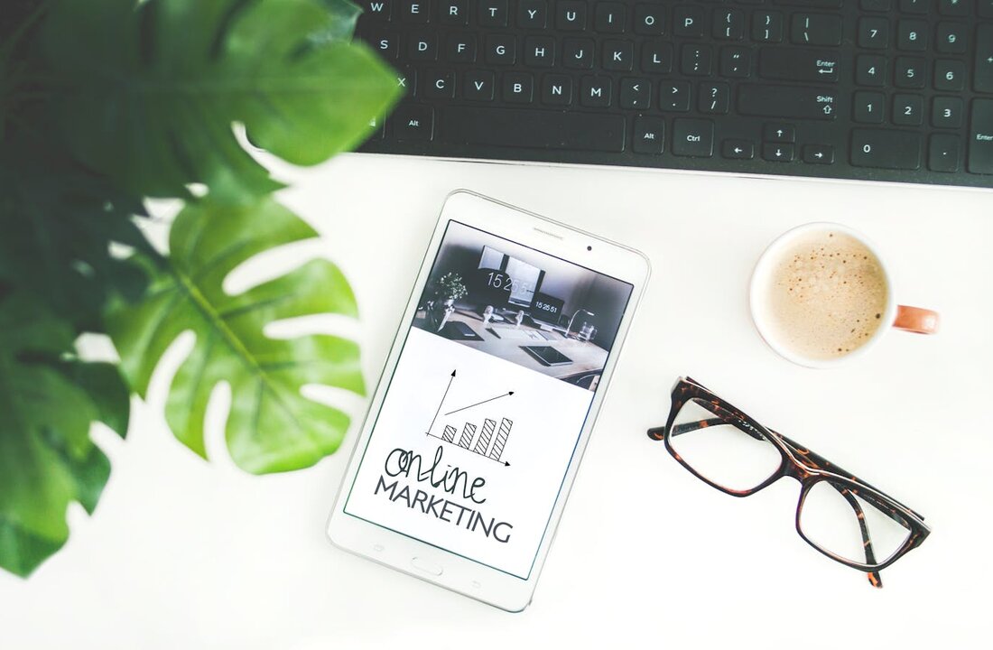 Tablet showing online marketing graphic with growth chart next to keyboard, plant, and coffee — Bergen County online marketing strategy